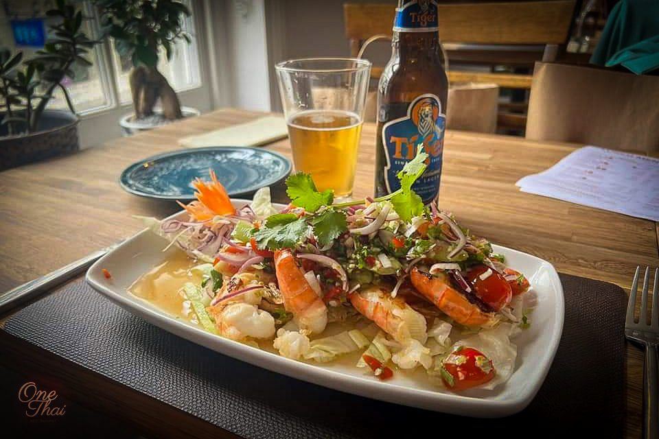 Sweetwater king prawns with Fresh thai dressing and bottle of TIger beer on table in One Thai Restaurant