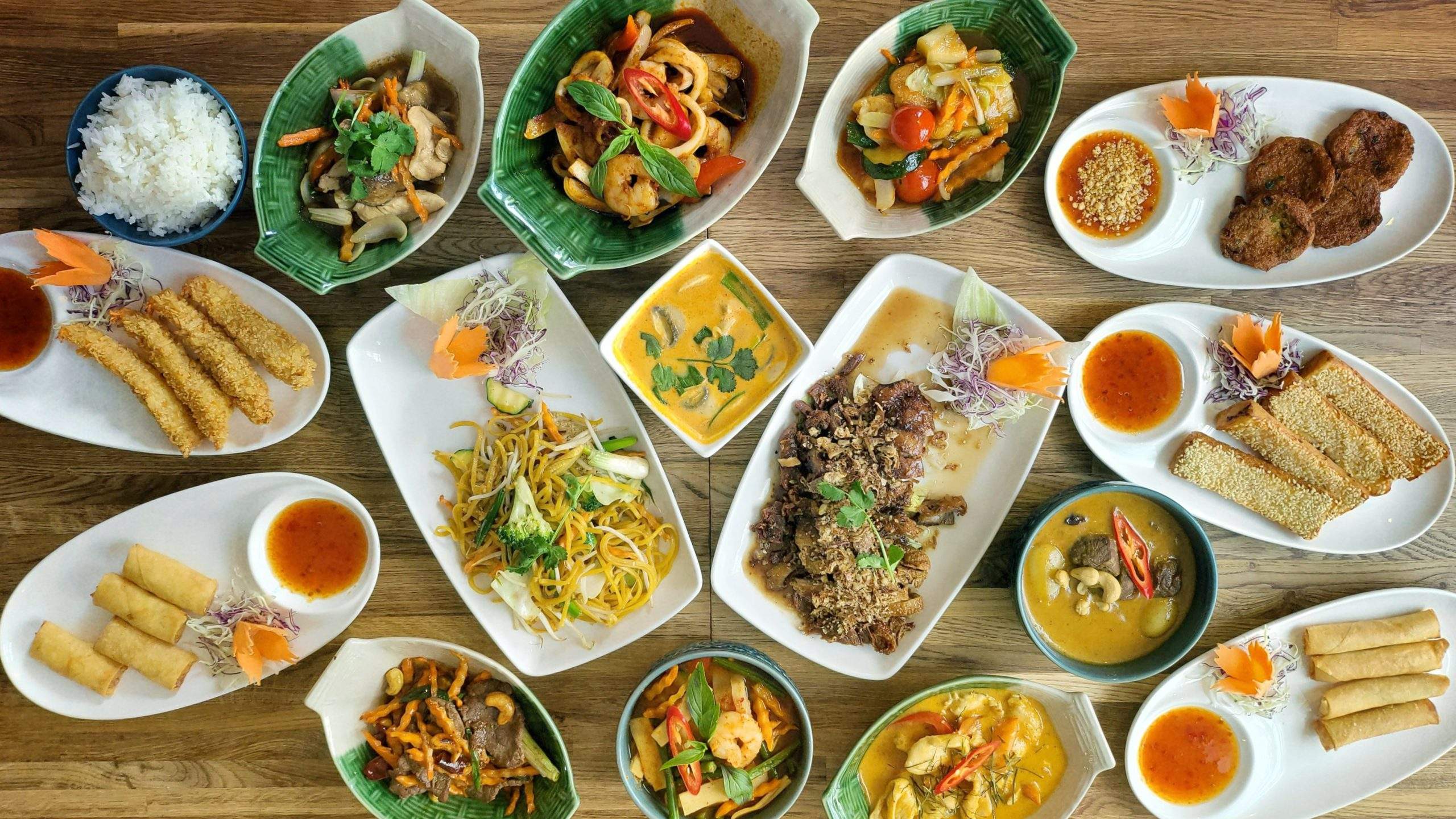 Table with selection of dishes from One Thai Restaurant, showing curries, starters and stir fries, including tempura prawns, fish cakes, Seafood stir fry and prawn on toast among 15 dishes.