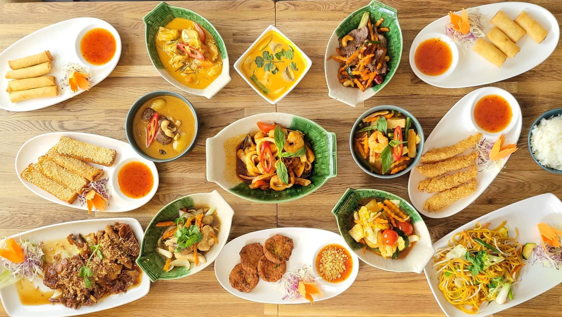 Table with selection of dishes from One Thai Restaurant, showing curries, starters and stir fries, including tempura prawns, fish cakes, Seafood stir fry and prawn on toast among 15 dishes.